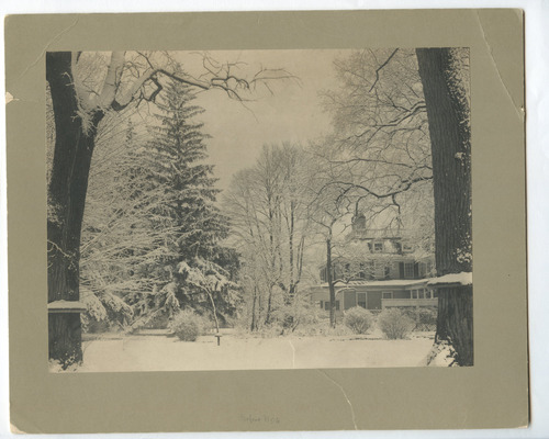 Black and white photograph of trees in snow with Georgian mansion in the background.