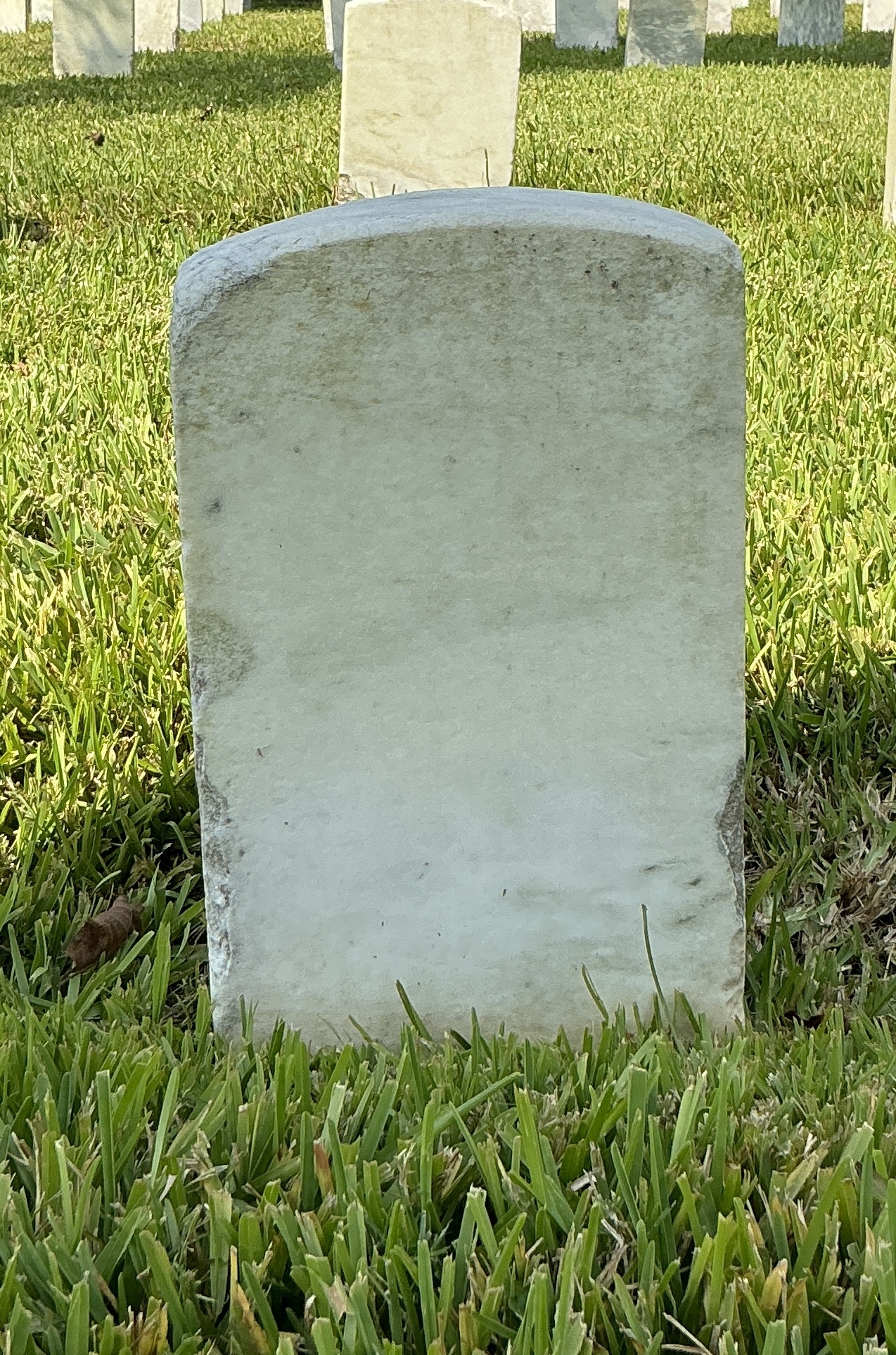 Back of historic upright marble headstone with recessed shield face.