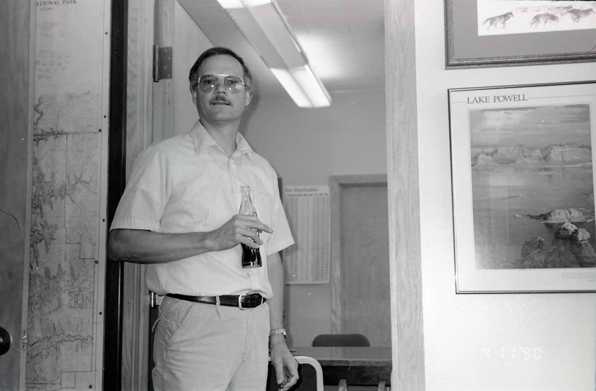 BW Photos of Interpretation Personnel. Man standing with drink in doorway.