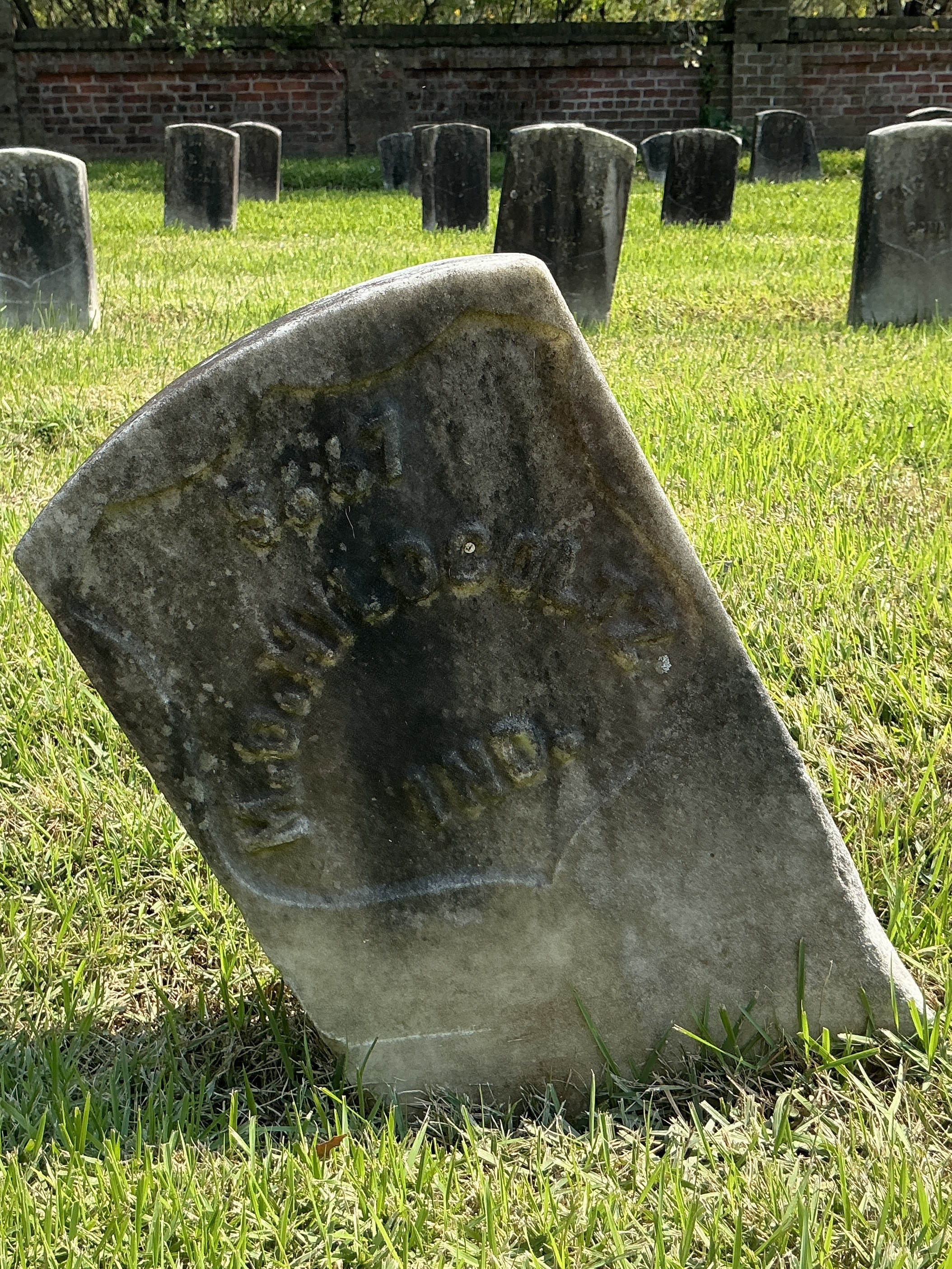 Front of historic upright marble headstone with recessed shield face.