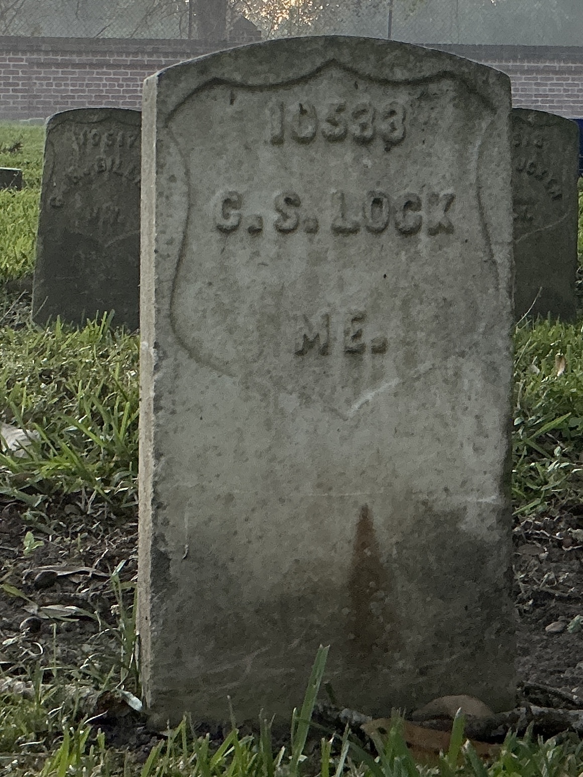 Front of historic upright marble headstone with recessed shield face.