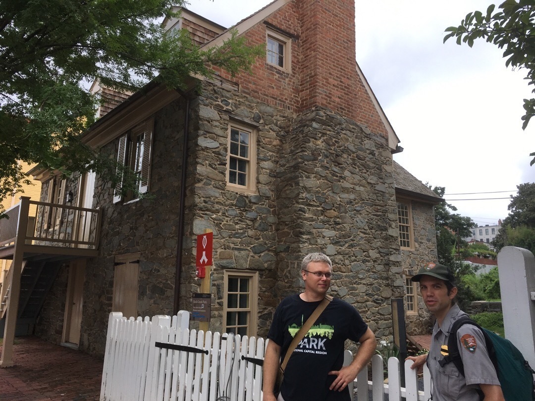 A three story stone house with a chimeny and several windows.