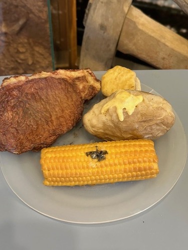 Tactile dinner plate display featuring steak, biscuit, baked potato, and ear of corn