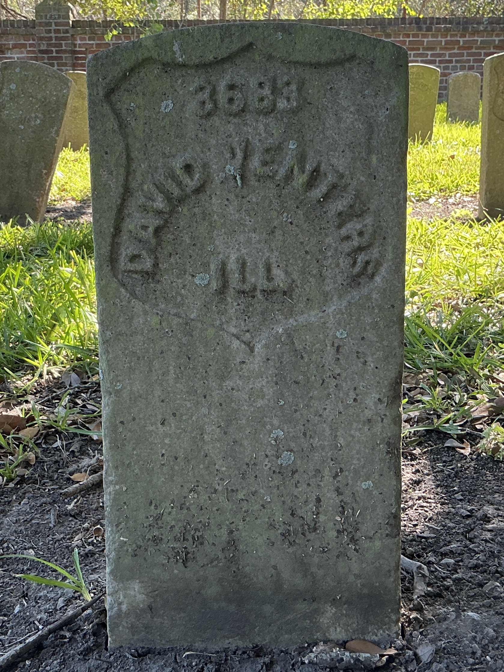 Front of historic upright marble headstone with recessed shield face.