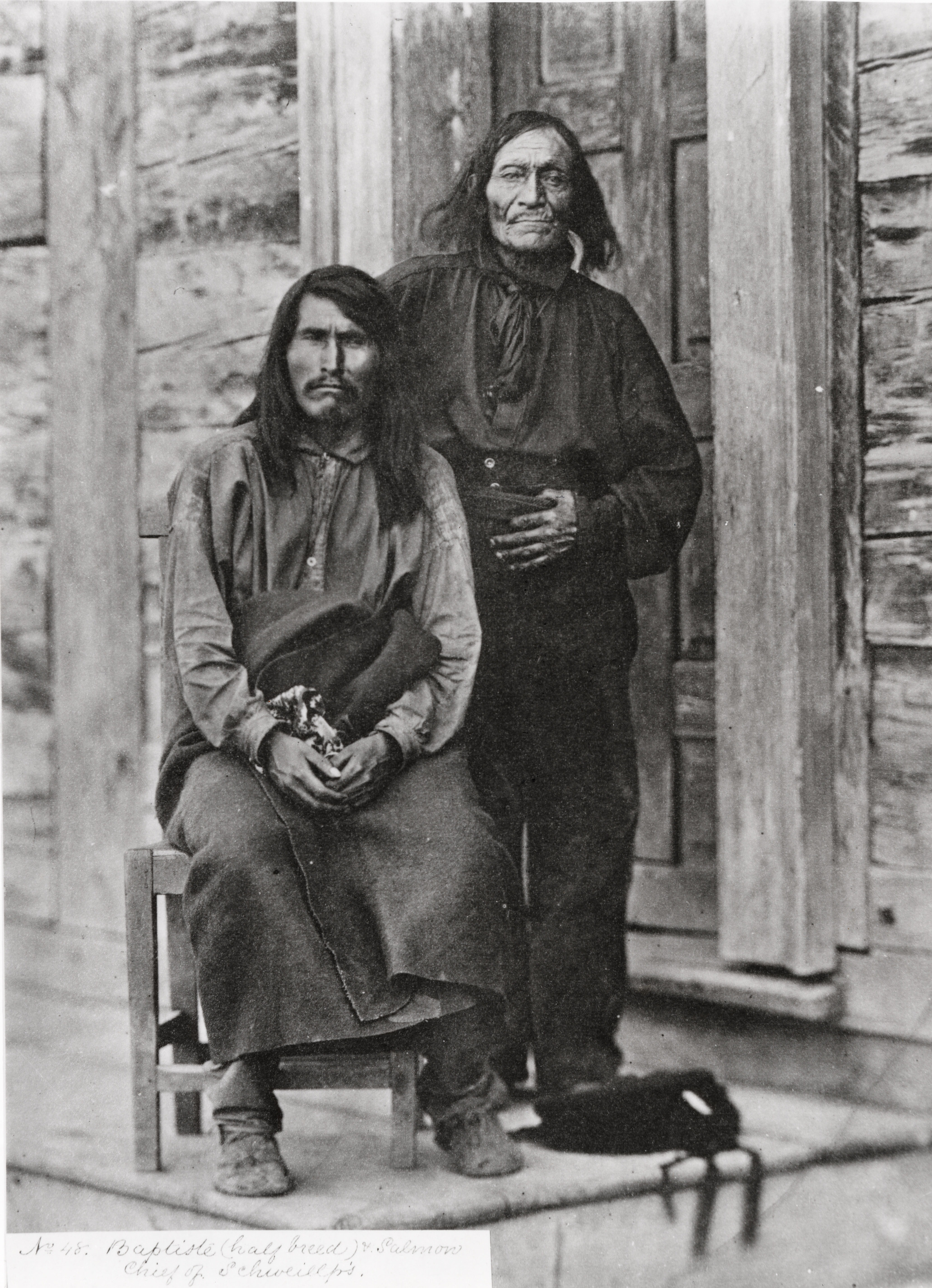 Black and white photograph of two people, one sitting and one standing