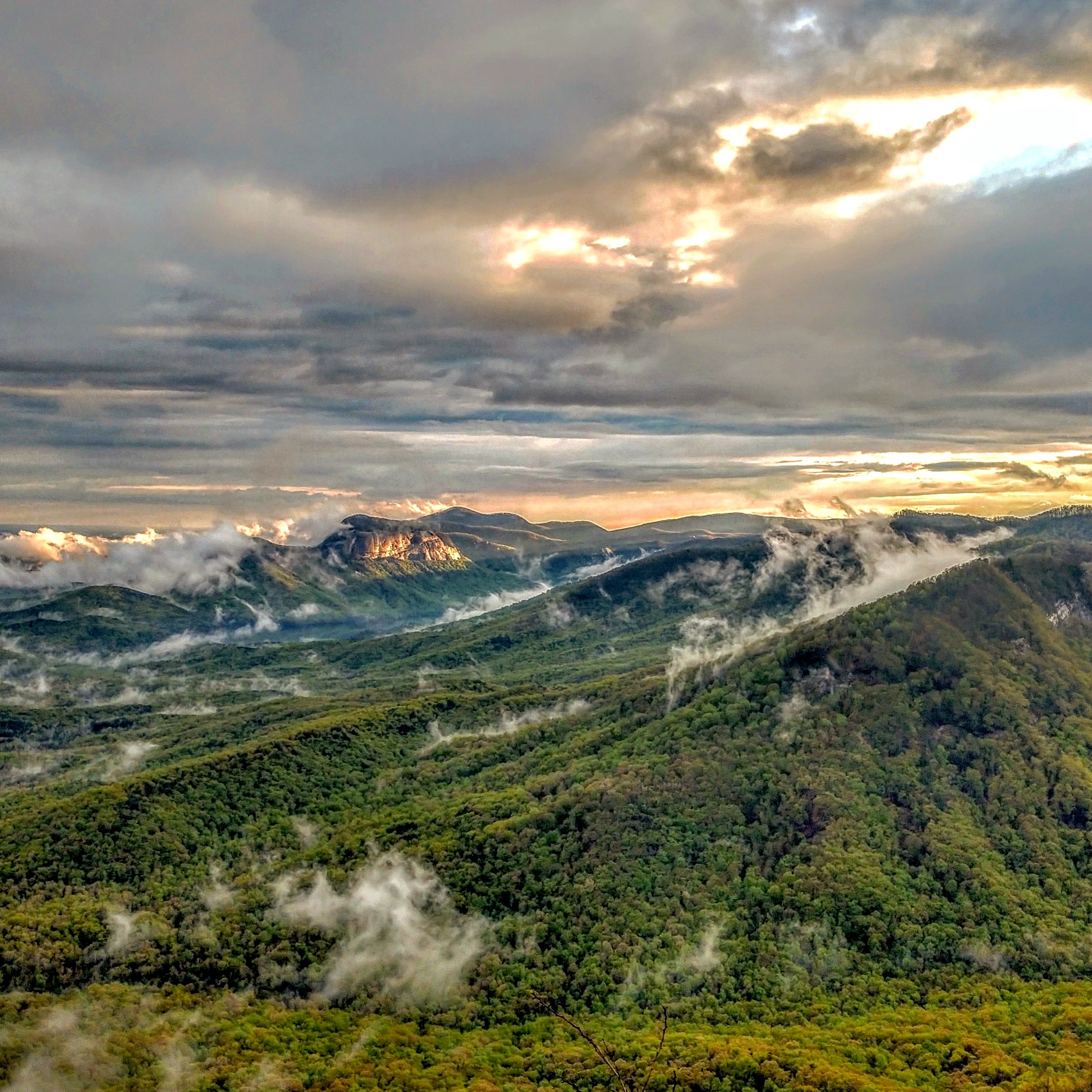 Mountainous region with lowhanging clouds during a sunrise.