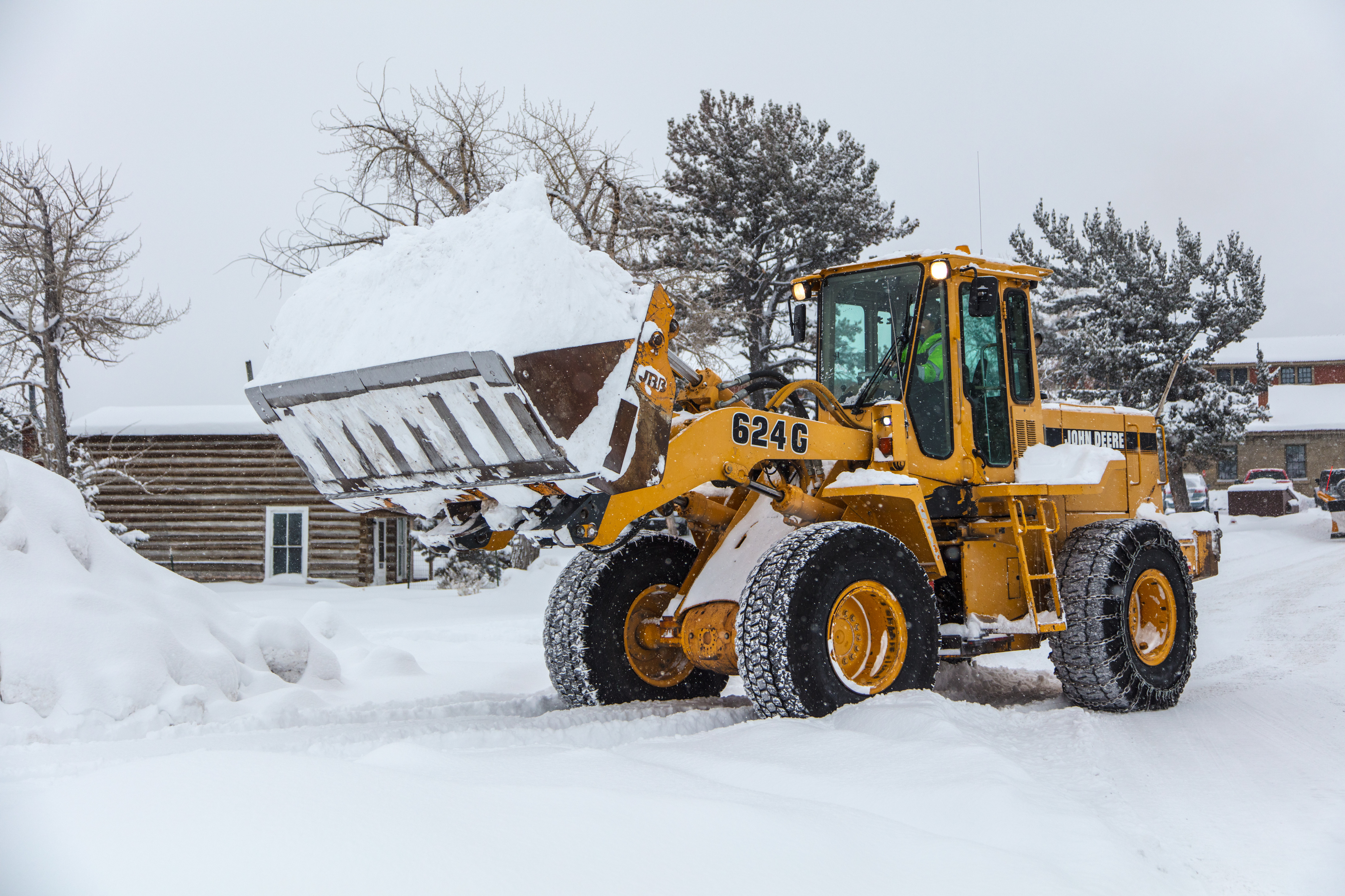 A front loader has a bucket full of snow