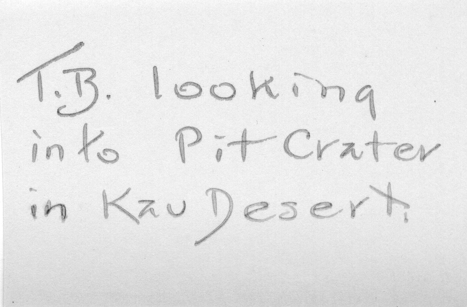 The backside of an image of Thomas Boles near a pit crater. There is a caption in the center of the image, "T.B. looking into Pit Crater in Kaʻu Desert."