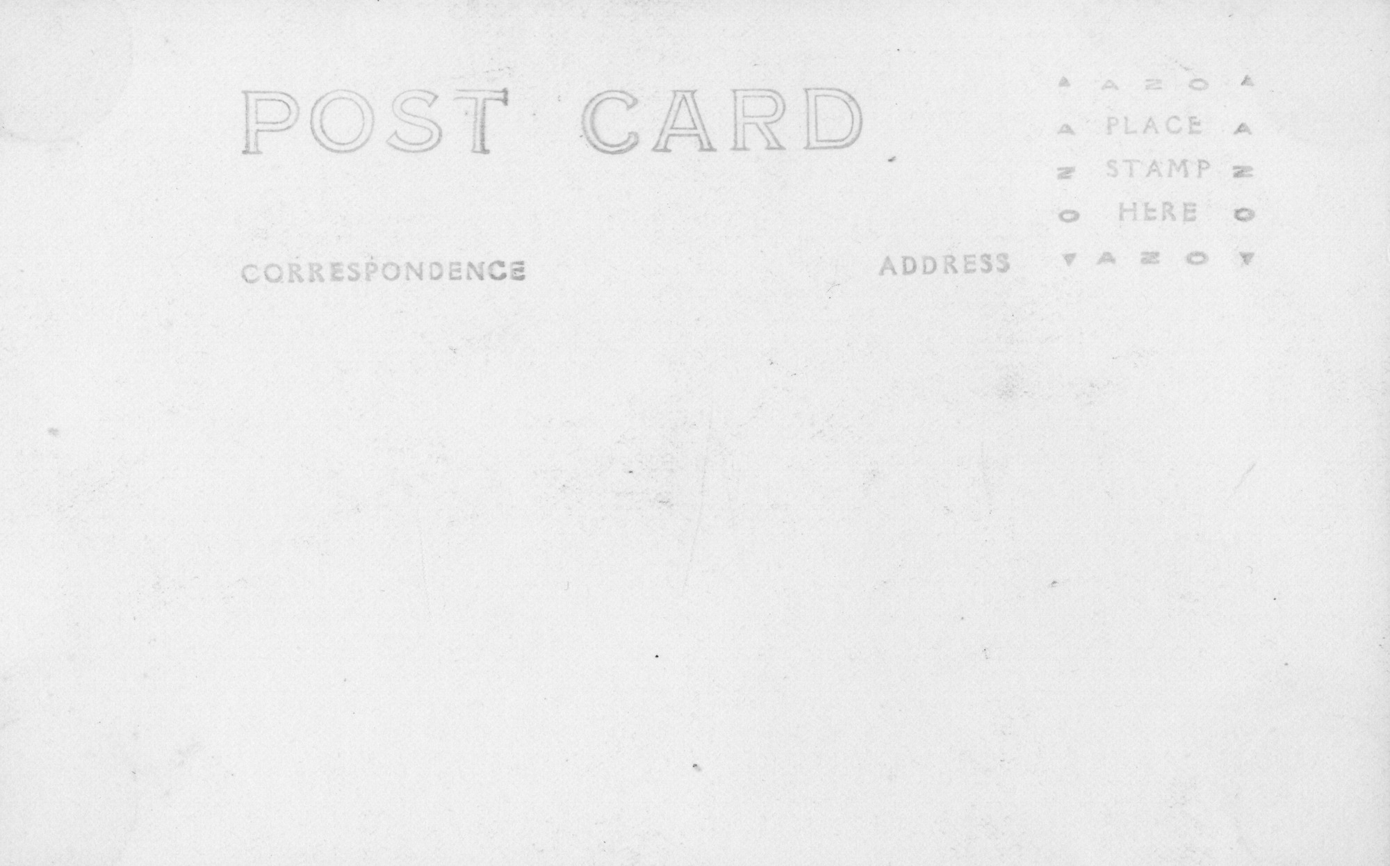 The back of a postcard. The words "Post Card" are centered on the card, along with the subtitles "Correspondence" and "Address" under it. There is a box outlined with "AZO" and triangles on each corner, with the instructions "Place stamp here" at the center. There is no address, correspondence, or stamp. It shows slight signs of age, such as darker spots and faded print.