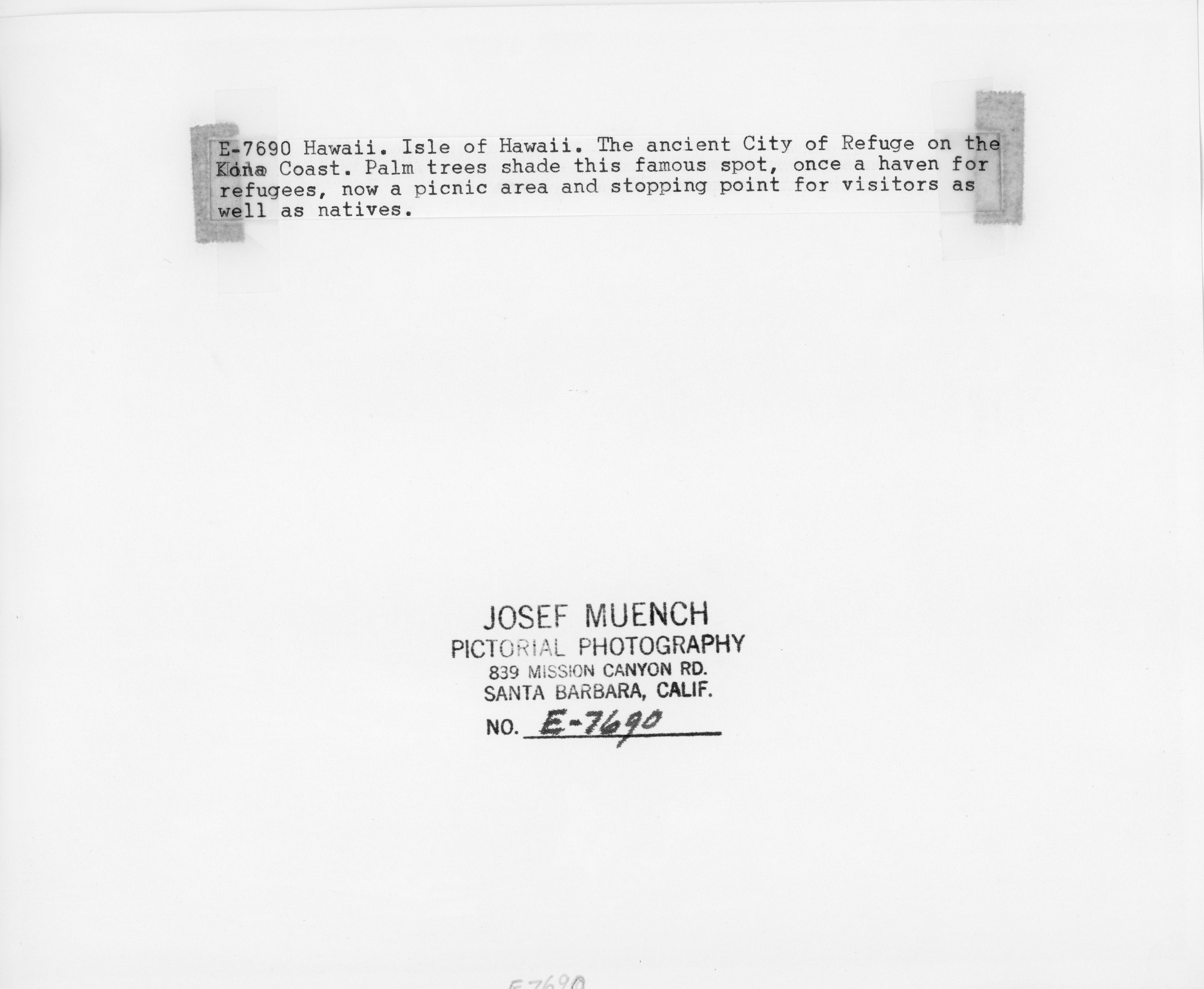 The back of an image of three women sitting on the shore of the beach. There is text on the back of the image that reads, " E-7690 Hawaii. Isle of Hawaii. The ancient City of Refuge on the Kona Coast. Palm trees shade this famous spot, once a haven for refugees, now a picnic area and stopping point for visitors as well as natives.” At the bottom, it has the photographer's name, “Josef Muench,” where the image was produced, “Pictorial Photography, 839 Mission Canyon Road. Santa Barbara, California," and the number assigned to the image, "E-7690."