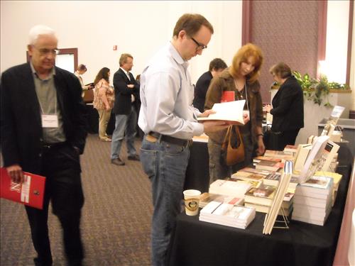 A group of scholars look at various tables featuring books and area information.