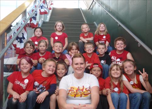 Students and their teacher sit on the stairs at the Heritage Center for a class photo.