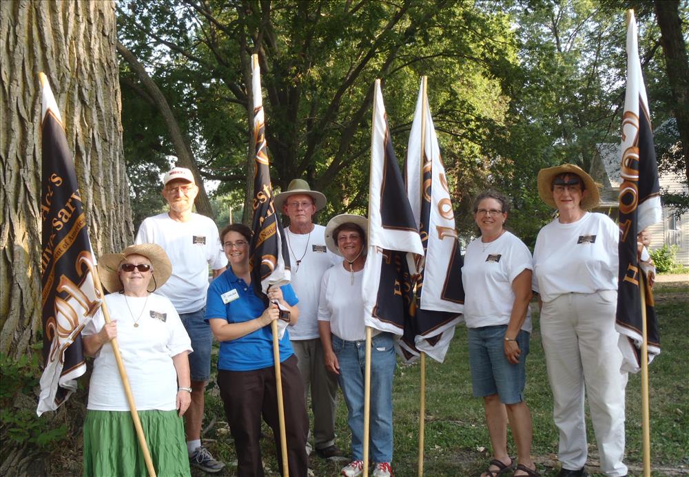 A group of volunteers and a SCA intern holding flags for the 150th Anniversary of the Homestead Act.