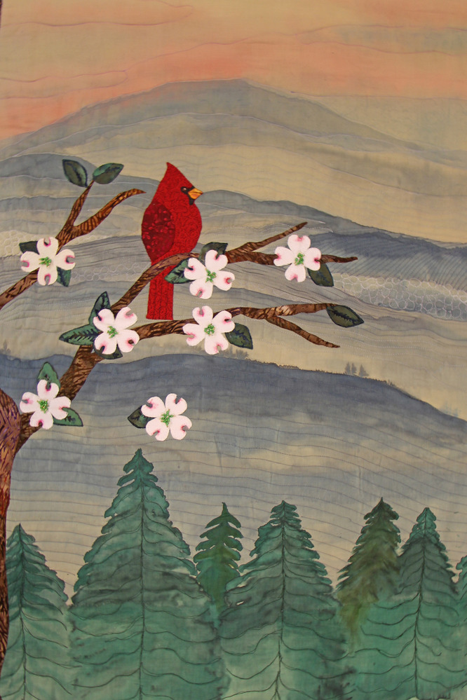 A cardinal sits in a tree before a mountain