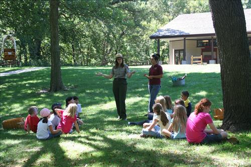 Children sit in two groups while a Ranger explains how to play a game.