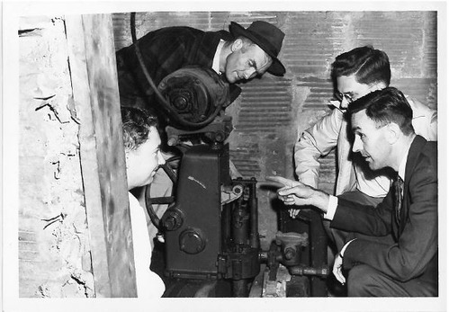 Four individuals gather around a piece of machinery