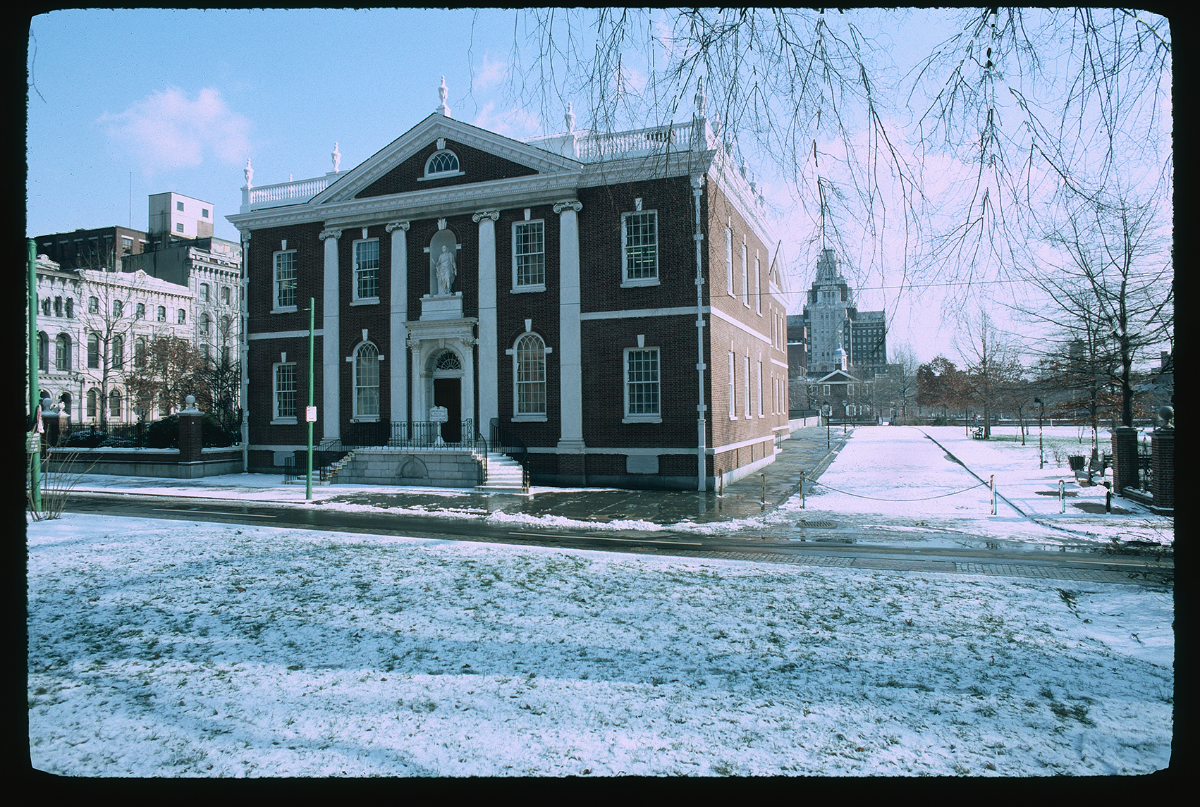 Library Hall. Exterior. Front face. Looking east across 5th Street. Carpenters Hall in background to right, with Custom House behind it. Snow on ground.