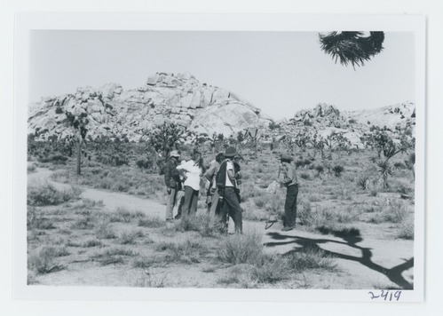 Black and white image of Conducted hike in Barker Dam area. Reino Clark leading visitors.