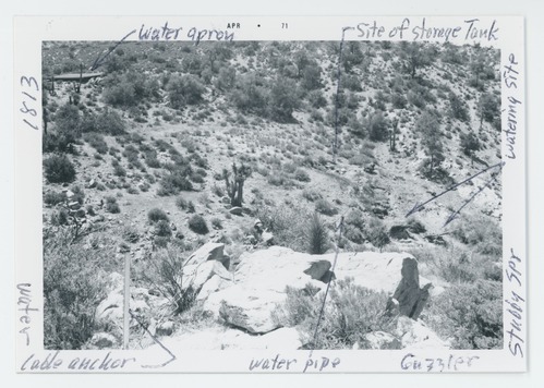 Black and white image of guzzler and old water catchment basin in the wash