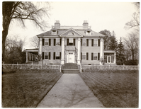 Facade of Georgian house with lawn in front, one of the flanking porches glassed in