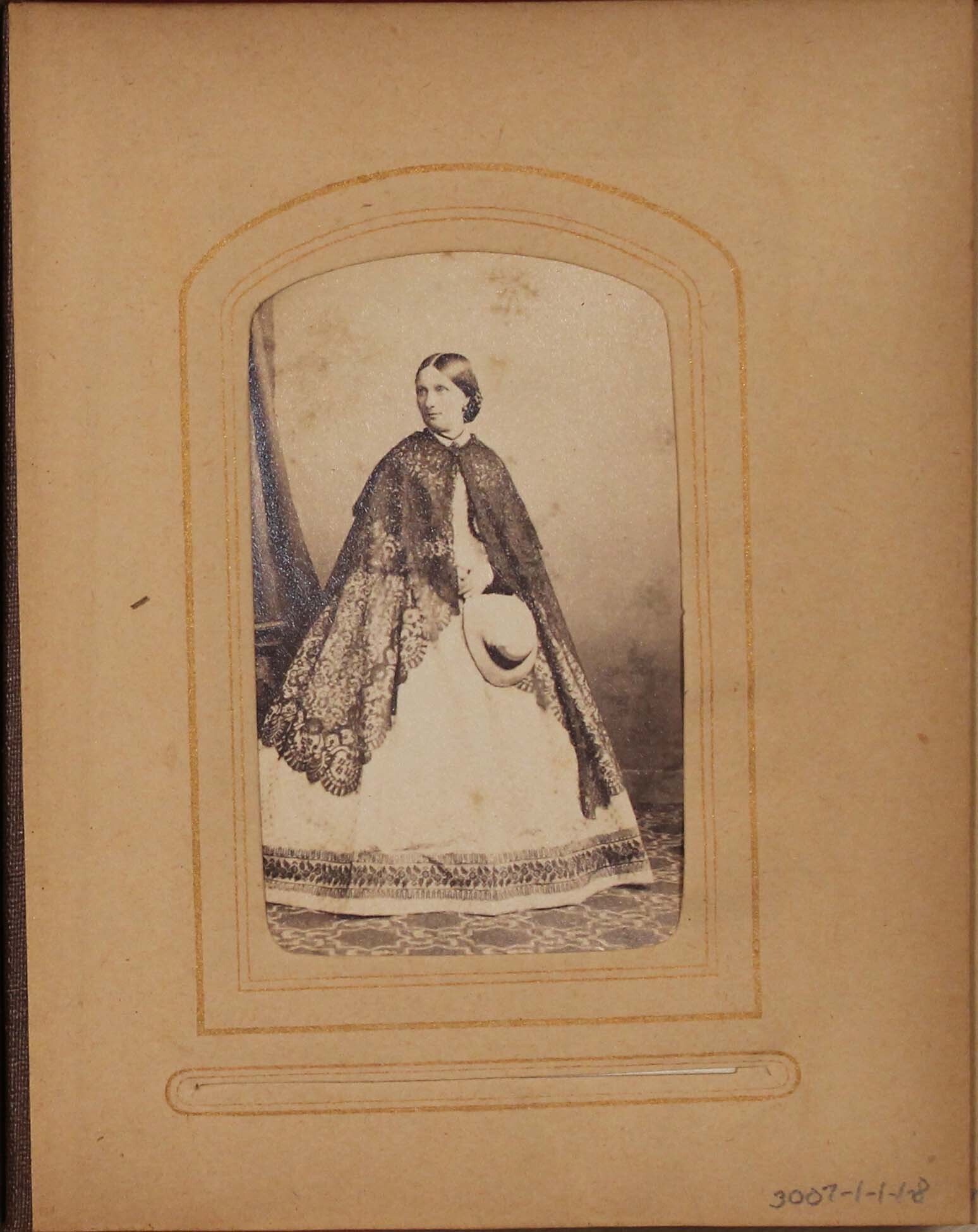 Black and white photograph of woman holding hat.