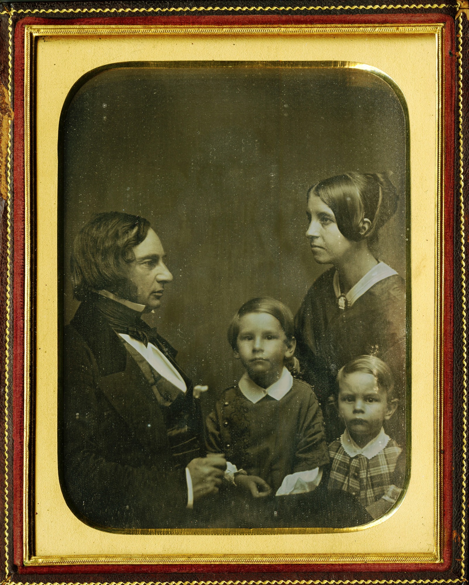 Group portrait of a man and woman in profile and two small boys facing camera.