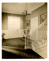 Front hall of house with intricate white banister to the right.