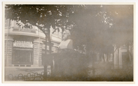 Henry Wadsworth Longfellow statue situated in triangular outdoor plaza. Plaza has grass and trees. Photograph shot from the statue's left; building labeled 
