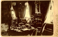 Black and white photograph of small crowded 19th century sitting room.