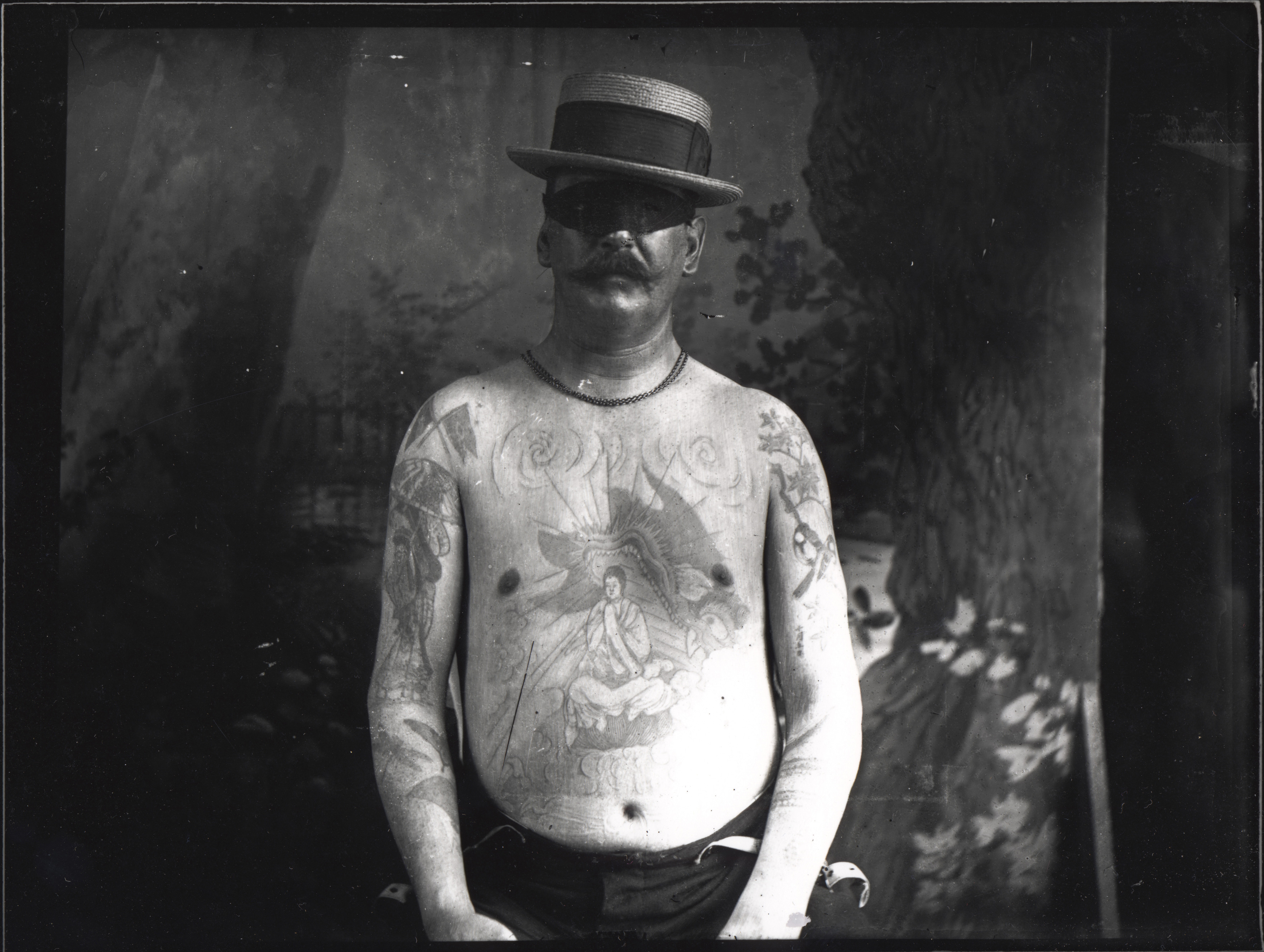 Shirtless man showing large chest tattoo of Buddhist deity in a dragon's mouth.