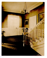 View of front door taken from beside intricately carved staircase.