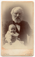 Henry Wadsworth Longfellow is seated, holding a very young baby in his lap. Baby smiles while wearing a long white gown. Henry Wadsworth Longfellow's left arm rests on a table. He wears a dark suit and has ear-length white hair and a full white beard.