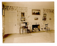 Black and white photograph of 19th century bedroom with fireplace.