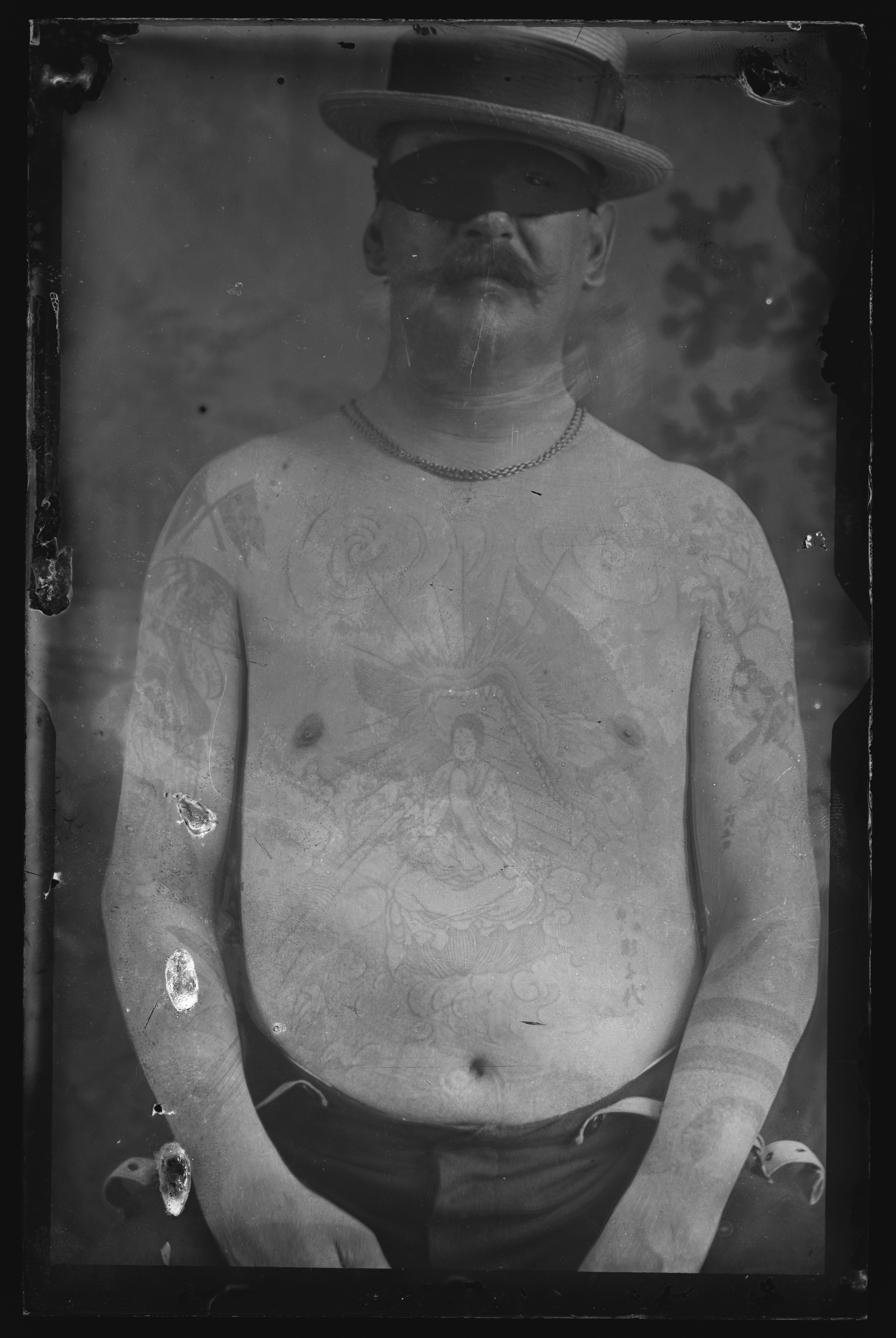 Shirtless man showing large chest tattoo of Buddhist deity in a dragon's mouth.