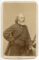Half-length portrait of Henry Wadsworth Longfellow standing at three-quarter view to his left. His left hand is placed on the head of an upholstered chair. His right arm draws aside his coat and is placed on his hip. Longfellow has chin-length graying hair and a mid-length graying beard.
