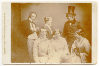 Group of six white people in formal attire posing for the camera. A man, woman, and Henry Wadsworth Longfellow stand behind a man and two women.