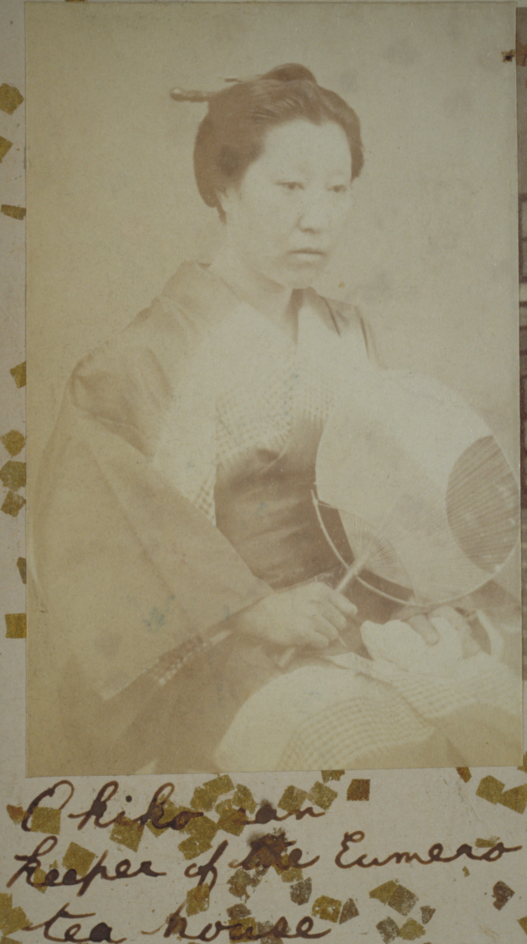 Sepia photograph representing a sitting Japanese woman holding a fan.