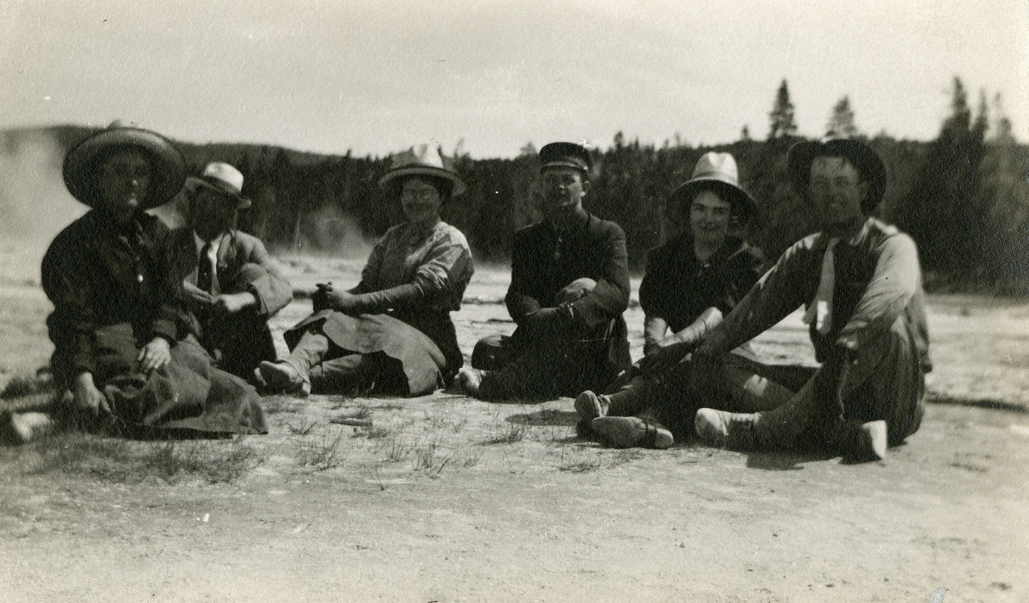 (Men and women seated near geysers)
