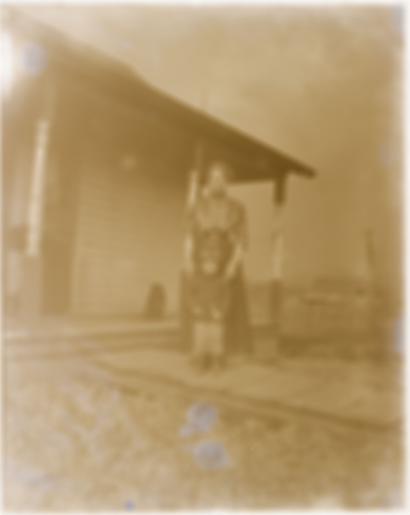 Very blurry image of woman and child in front of house.