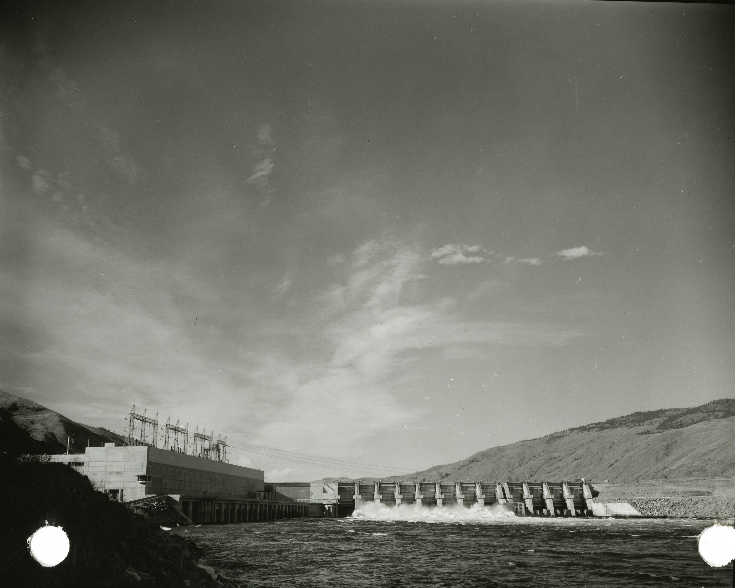 A dam with water spilling out into a lake.