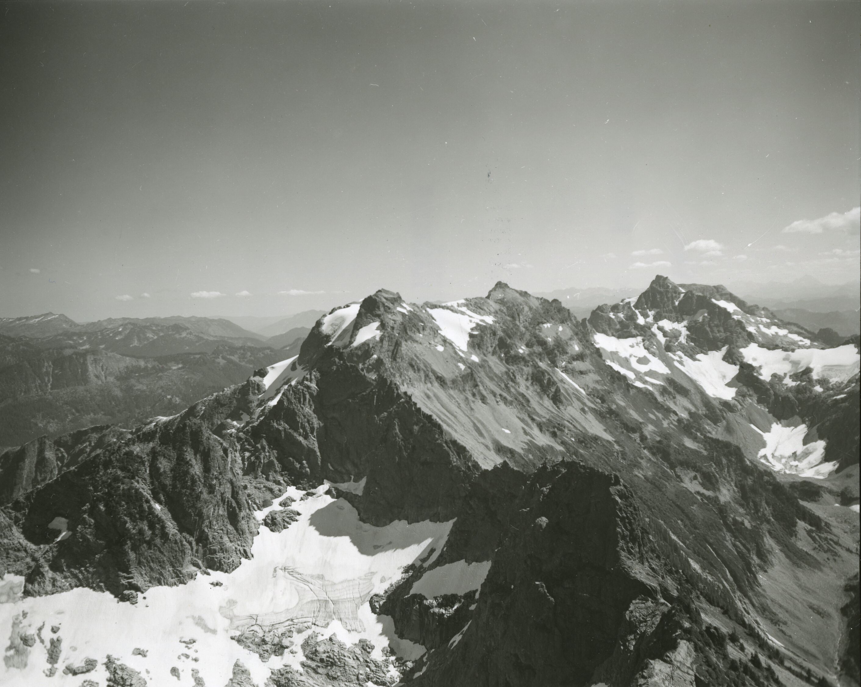 A ridge of steep mountain peaks with more mountains in the distance.
