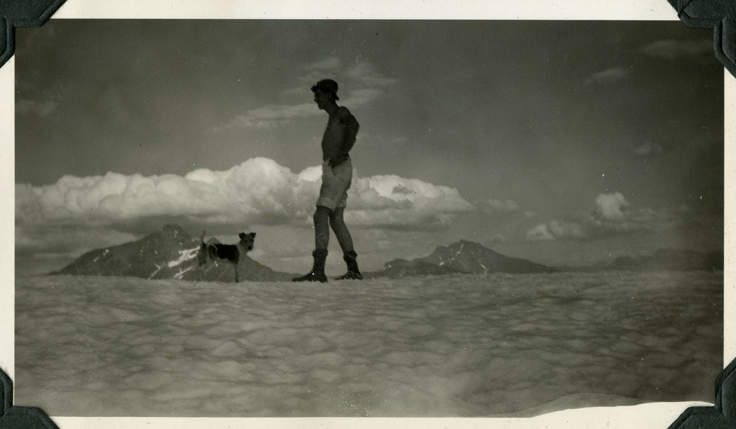 A man and a terrier standing on a snowfield.