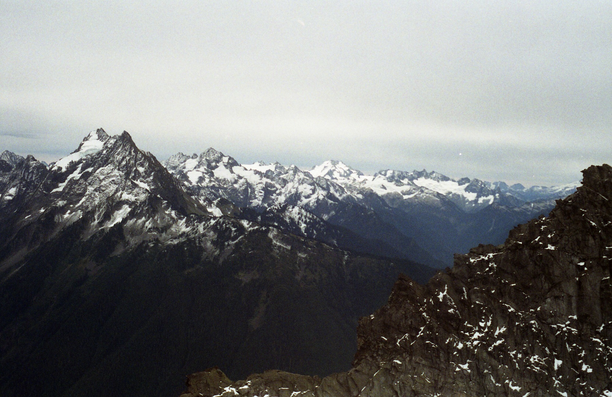 Snowy mountain ridges and peaks with forested sides and valleys.