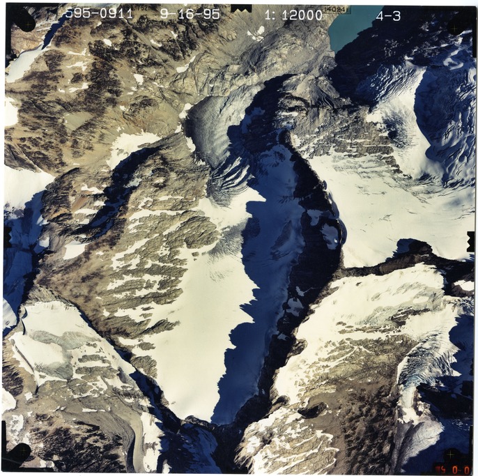 Color aerial photograph of glacier and snowfields on mountain peak.