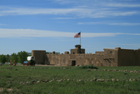 A brown building in the middle of a grassy field.