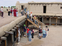 A group of people standing in front of an adobe building.