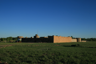 A adobe building in the middle of a field.