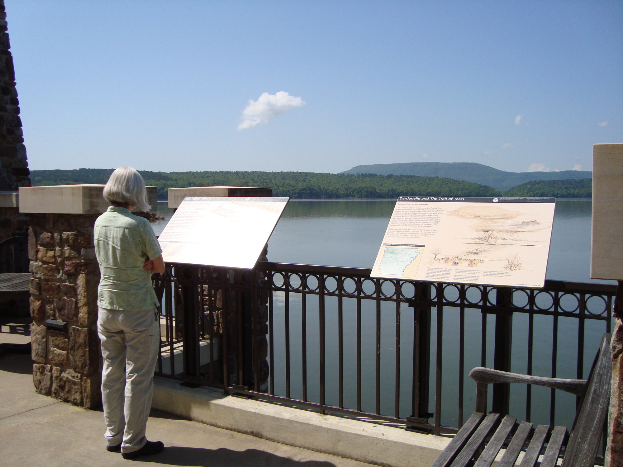 A person looking at a wayside in front of a body of water.