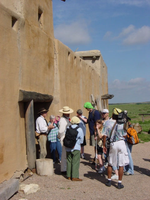 A group of people standing outside of an adobe building.