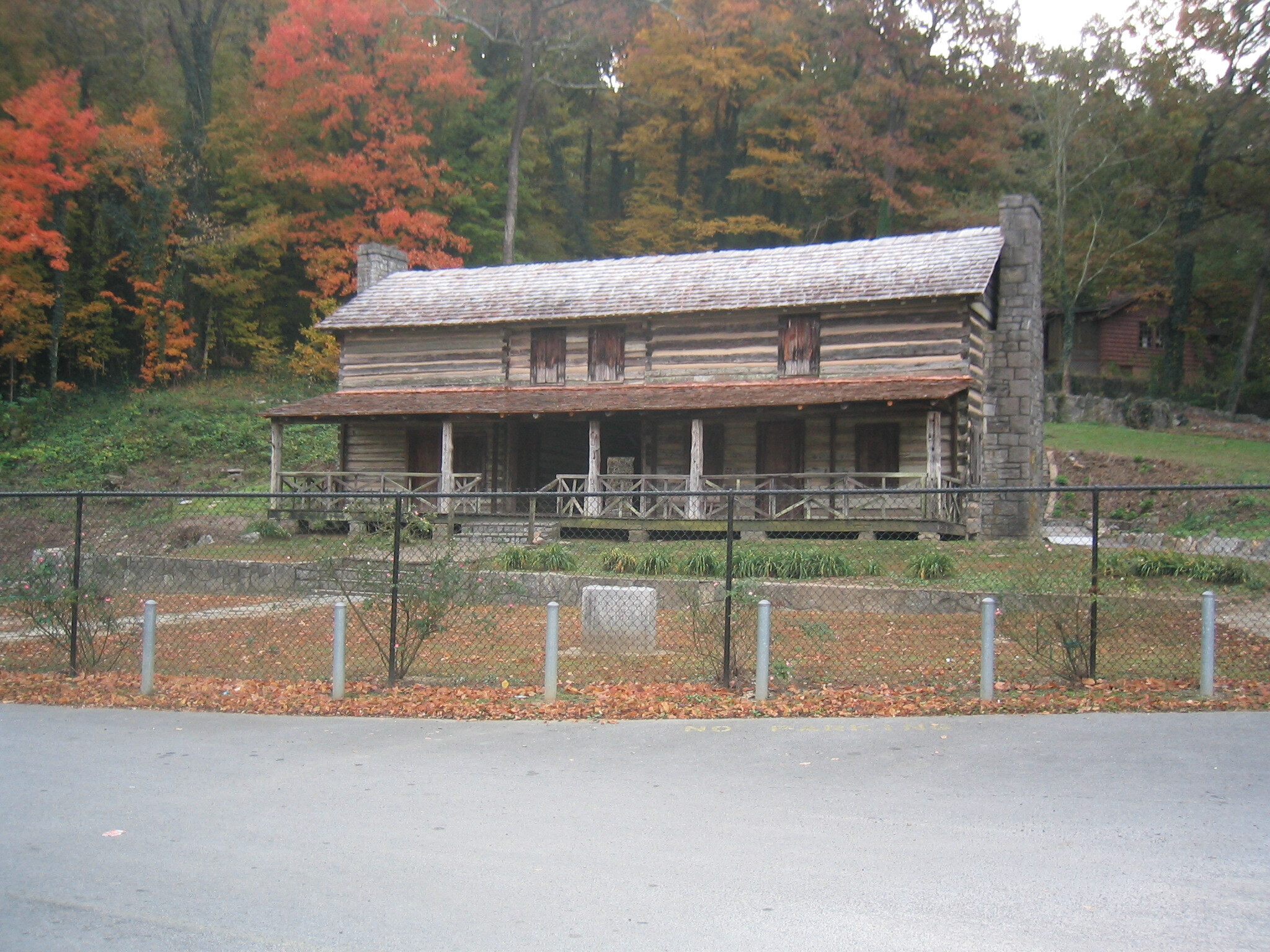 A wooden house in the woods beside a road.